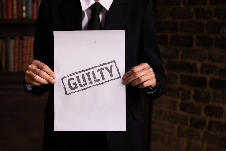 A businessman in a formal suit holding a sign with the word GUILTY.