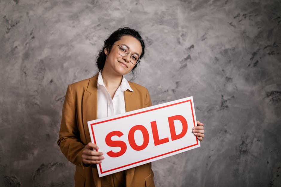 Confident real estate agent holding a 'Sold' sign indoors, symbolizing successful property sale.
